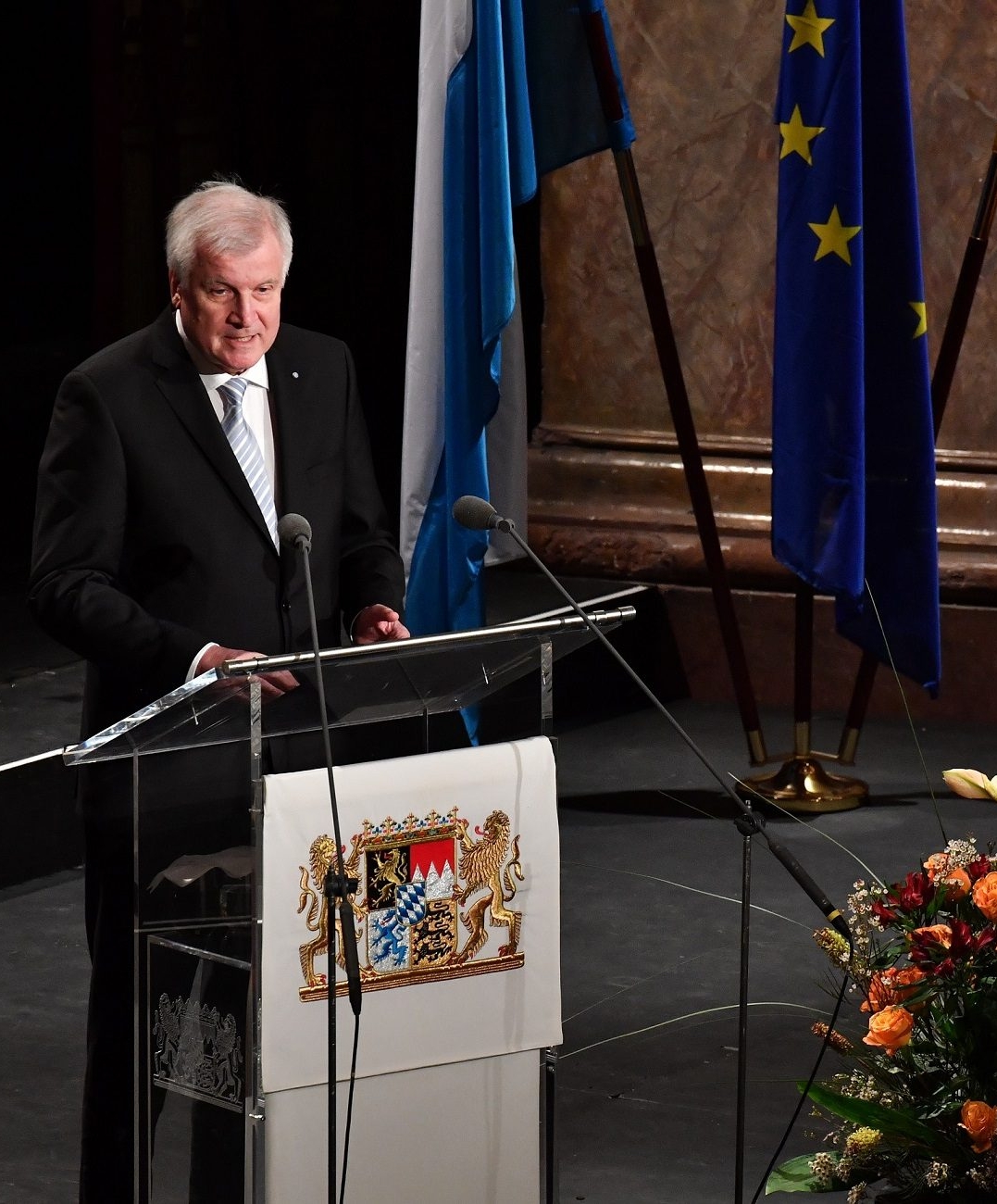 Vor dem Hintergrund der bayerischen und europäischen Flagge steht Ministerpräsident Horst Seehofer am Rednerpult beim Festakt im Nationaltheater in München am 1.12.2016.