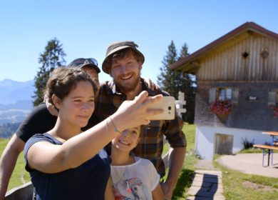 Familie macht Selfie vor Bauernhof.